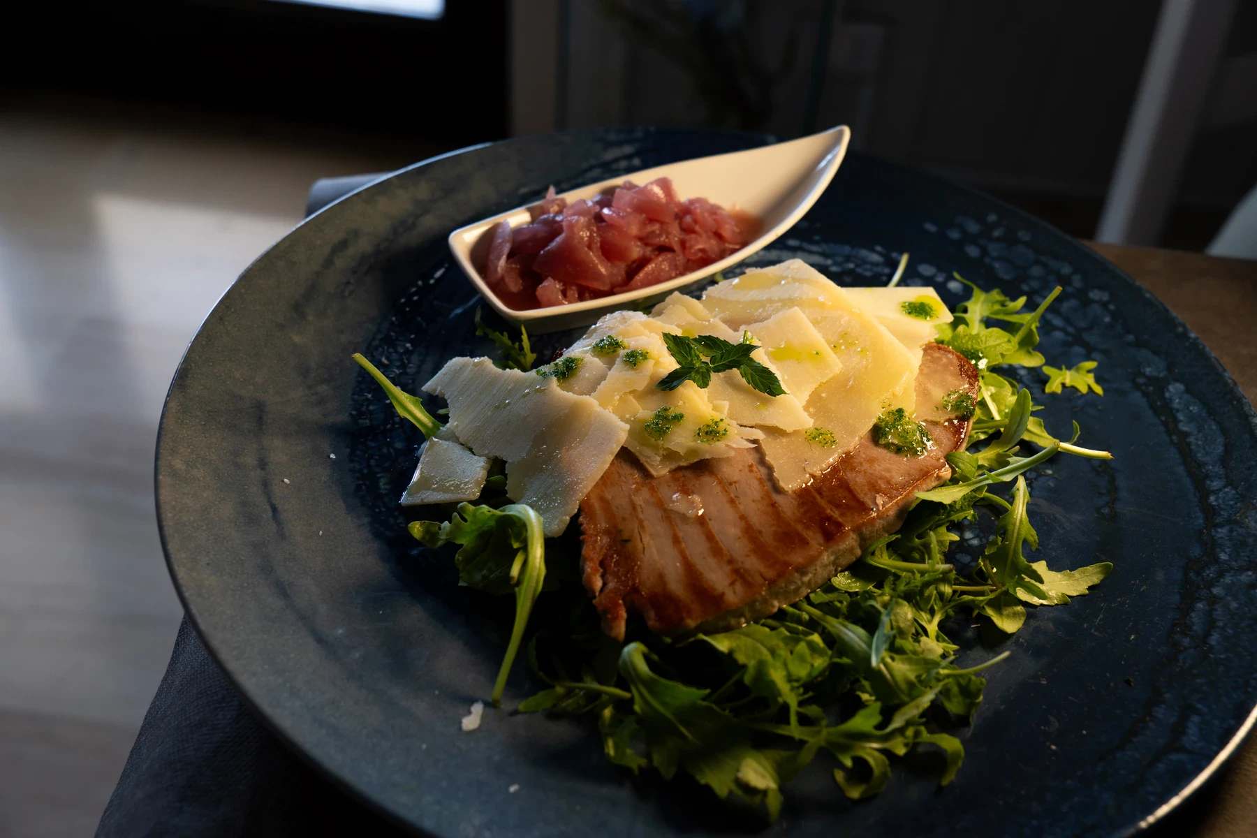 Tagliata di tonno scottato servita su rucola con scaglie di grana e cipolle caramellate