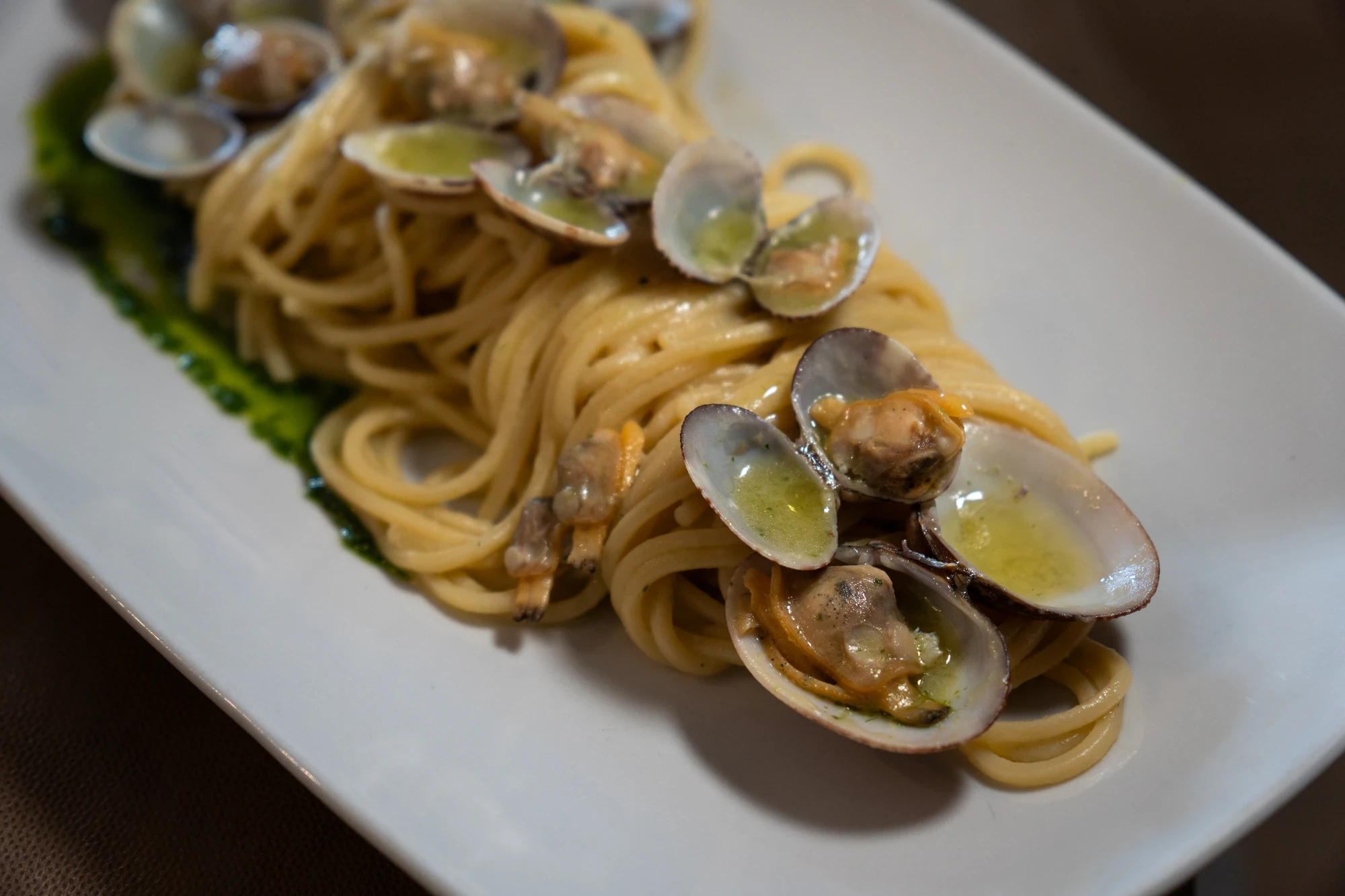 Spaghetti alle vongole impiattati su piatto bianco rettangolare