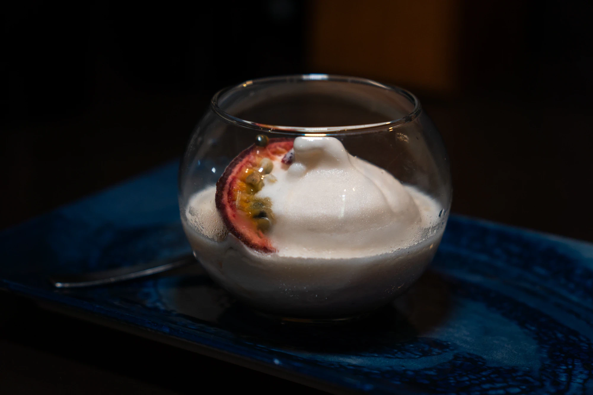 Dessert al cucchiaio con frutto della passione su piatto blu