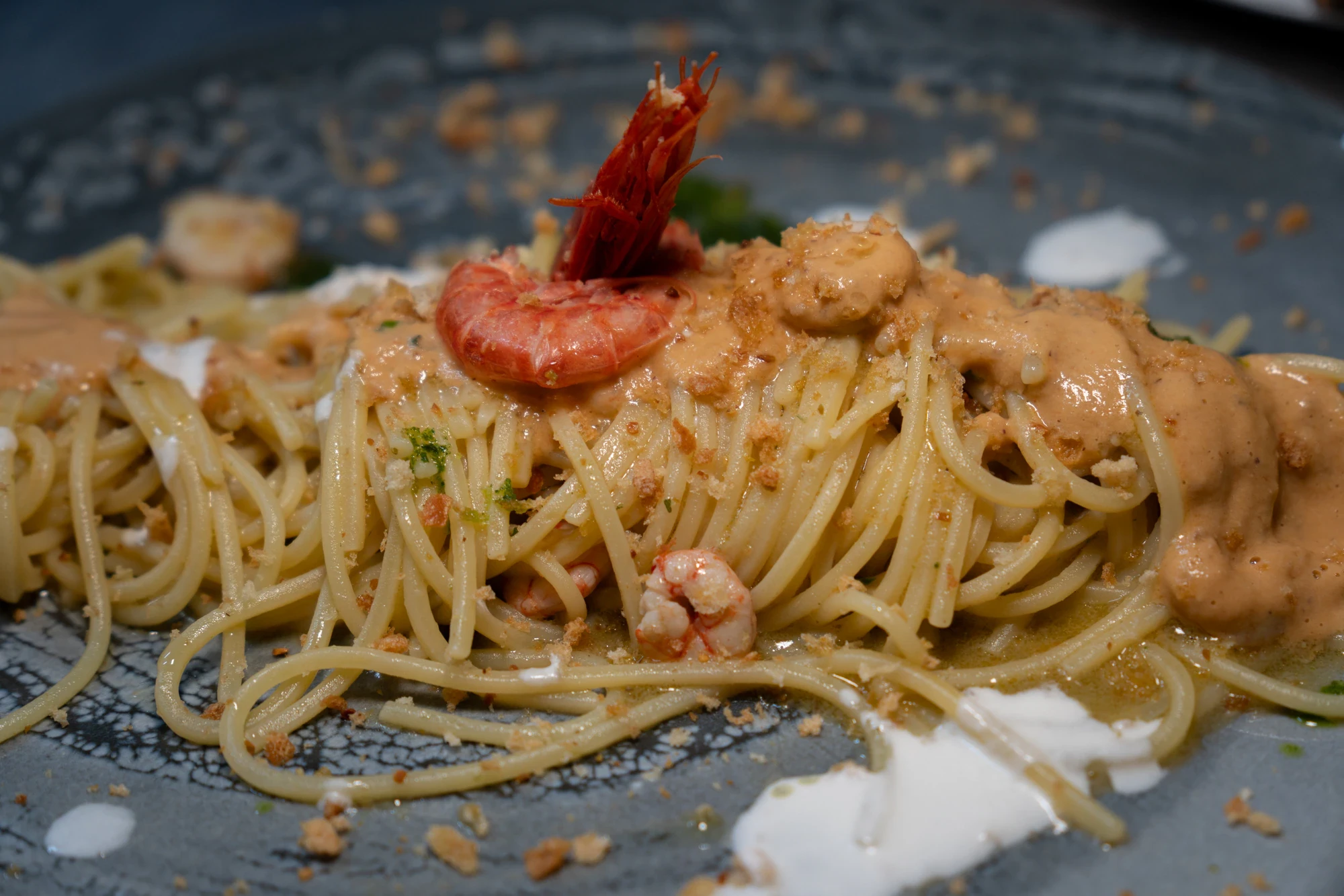 Spaghetti ai gamberi con crema di mare su piatto scuro